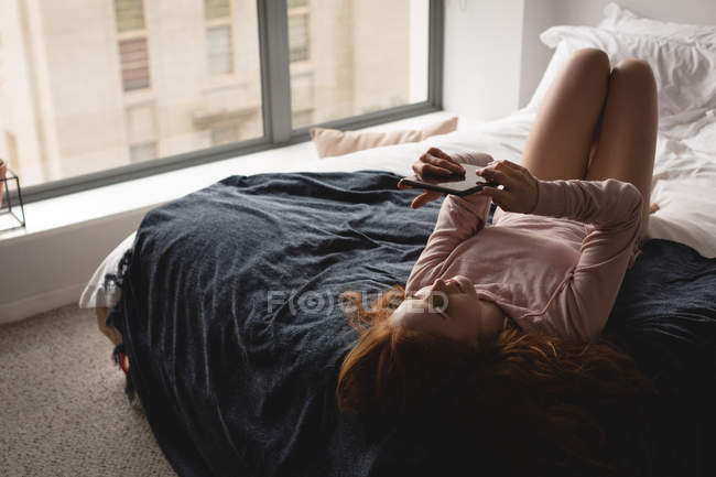 Женщина с цифровым планшетом в спальне дома — стоковое фото