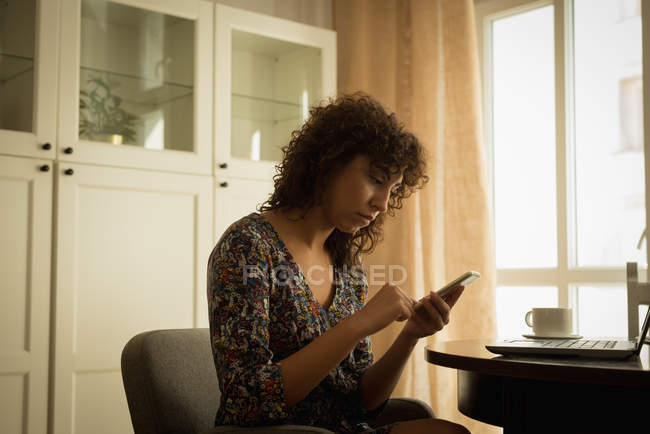 Mujer usando teléfono móvil en casa - foto de stock