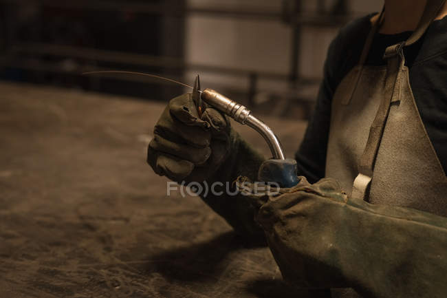Mid section of female welder holding welding torch in workshop. — Stock Photo