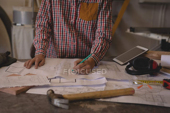 Mid section of craftswoman working with blueprints in workshop. — Stock Photo