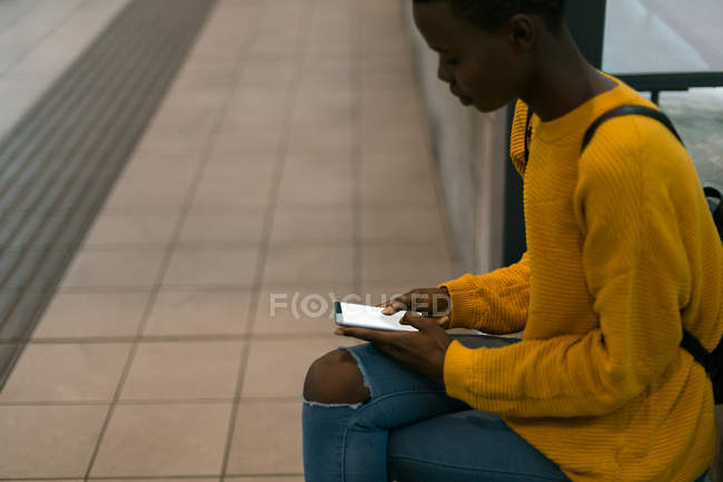 Молодая женщина использует мобильный телефон на тротуаре — стоковое фото