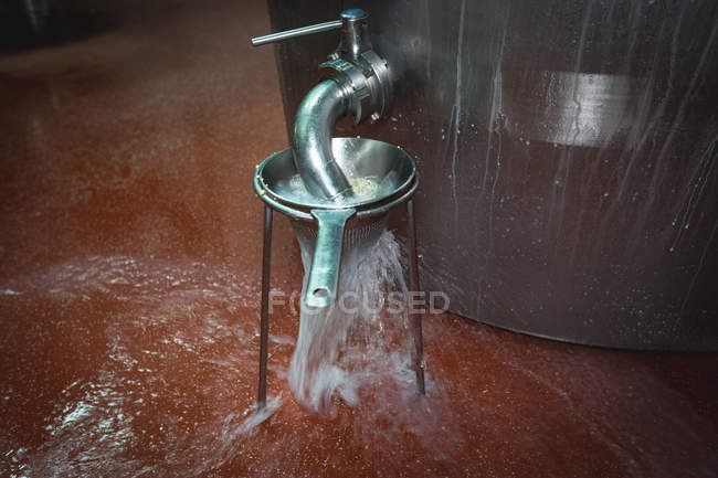 Liquid being filtered and overflowing from the tank in food factory — Stock Photo