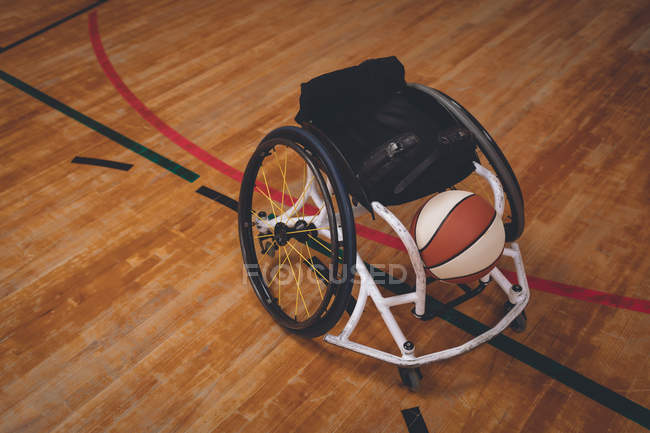 Sedia a rotelle vuota e pallone da basket in campo — Foto stock