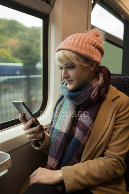 Donna che utilizza il telefono cellulare mentre viaggia in treno — Foto stock