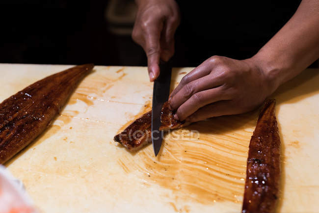 Chef filetea pescado en la cocina del restaurante en una tabla de cortar - foto de stock