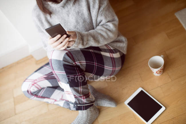 Крупним планом жінка, використовуючи мобільний телефон на підлозі вдома . — стокове фото