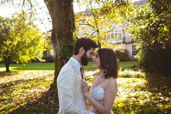 Романтическая невеста и жених смотрят друг другу в глаза в саду — стоковое фото