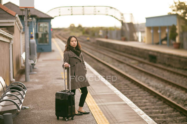 Женщина-руководитель ждет поезд с багажом на железнодорожной платформе — стоковое фото
