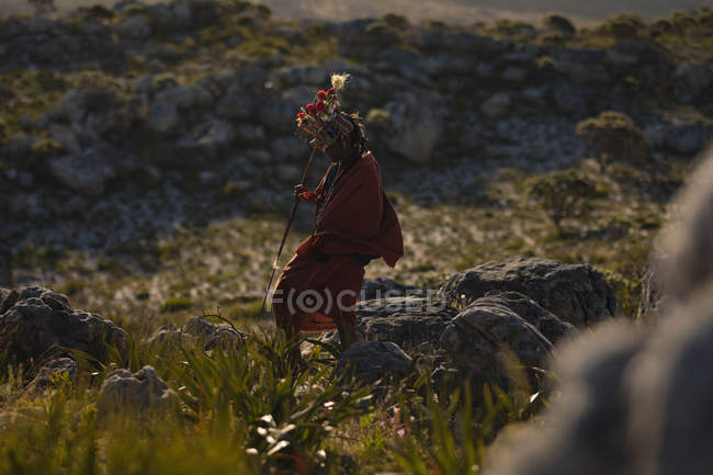 Maasai homem andando com pau no campo em um dia ensolarado — Fotografia de Stock