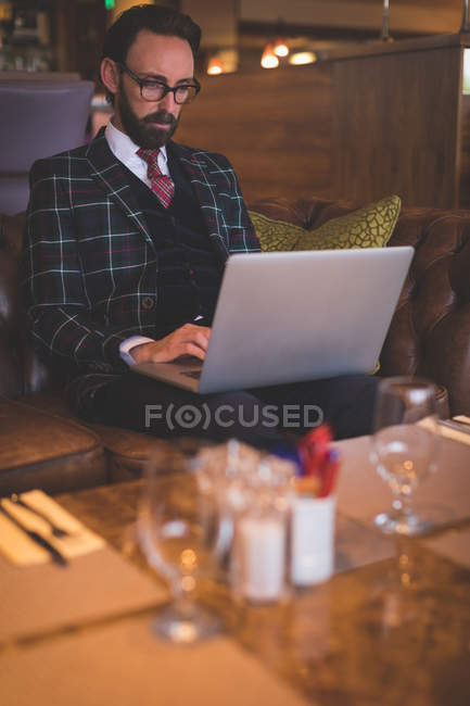 Businessman using laptop in bar — Stock Photo