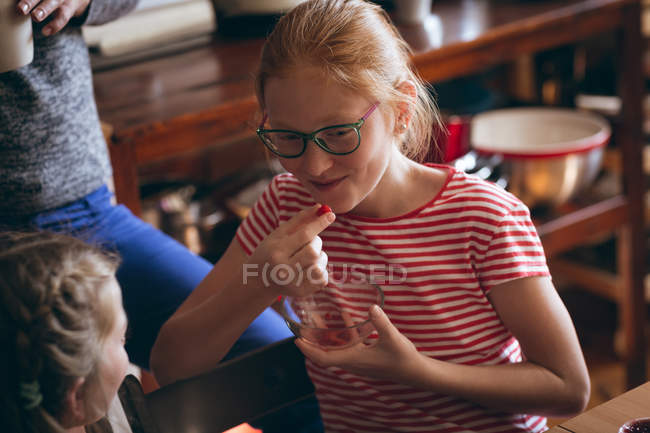 Chica en gafas tomando un aperitivo en casa - foto de stock