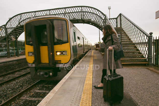 Женщина ждет поезд с багажом на железнодорожной платформе — стоковое фото
