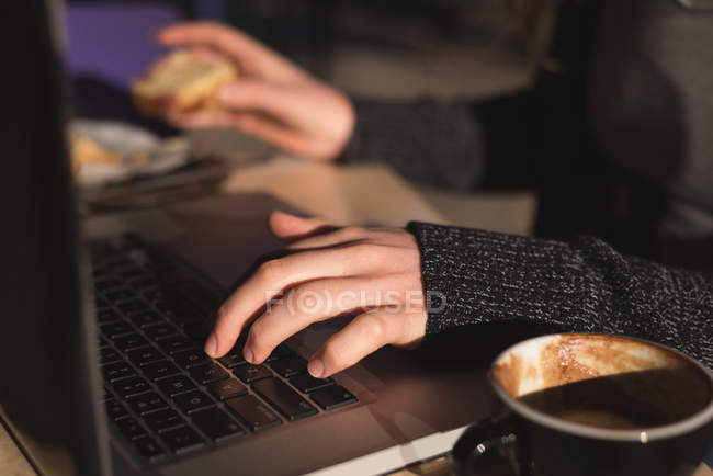 Mid section of woman using laptop while having coffee — Stock Photo