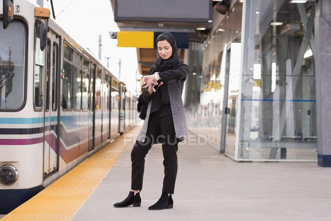 Mulher no hijab usando smartwatch na estação ferroviária — Fotografia de Stock