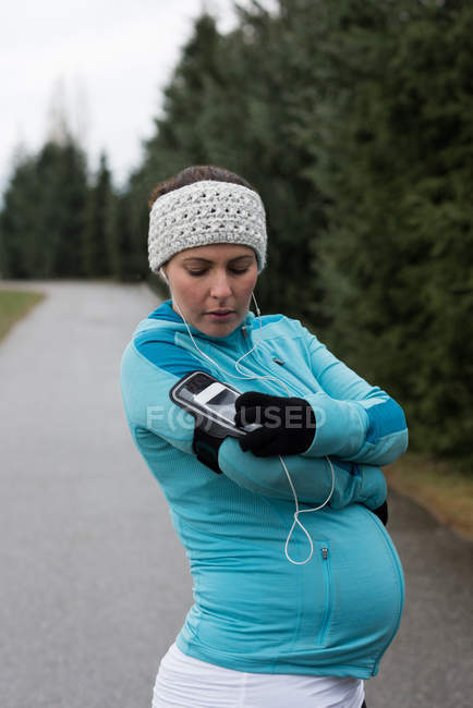 Mulher grávida usando telefone celular no parque — Fotografia de Stock