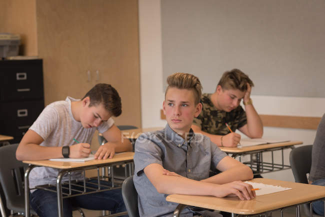 Pensativo adolescente sentado en el aula en la universidad - foto de stock