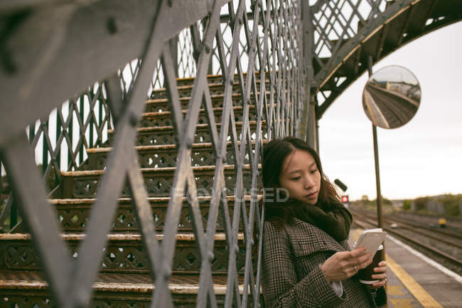 Hermosa mujer usando el teléfono móvil en forma de ferrocarril - foto de stock