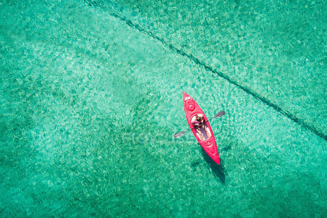 Каякер плавает на байдарках по мелкой бирюзовой воде в солнечный день — стоковое фото