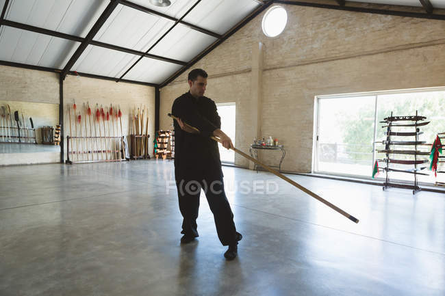 Боец кунг-фу практикуется с длинным полюсом в фитнес-студии . — стоковое фото