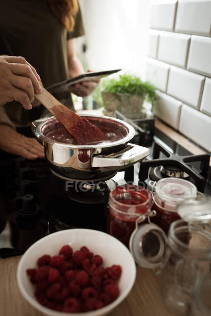 Бабуся і онука готують малинове варення на кухні вдома — стокове фото