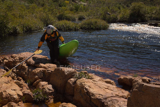 Woman walking with kayak boat and paddle by river. — Stock Photo