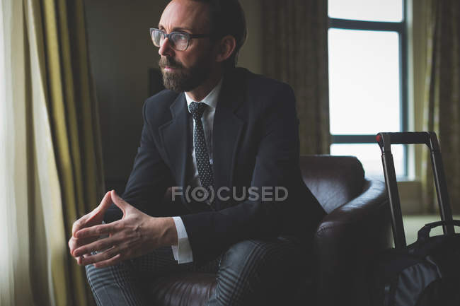 Homem de negócios atencioso sentado na cadeira de braço no quarto do hotel — Fotografia de Stock