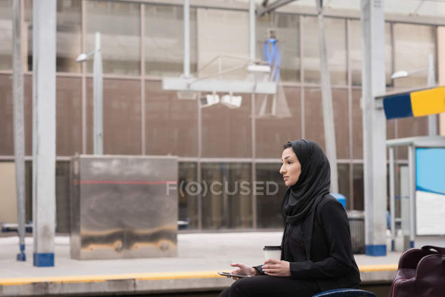 Donna in hijab utilizzando il cellulare alla stazione ferroviaria — Foto stock
