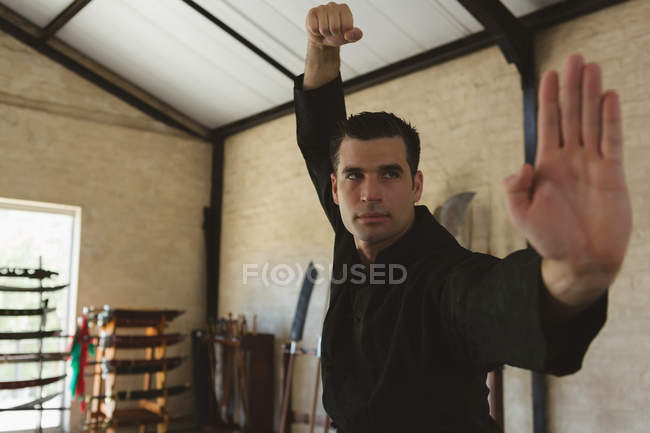 Combattant de kung fu pratiquant les arts martiaux en studio de fitness . — Photo de stock