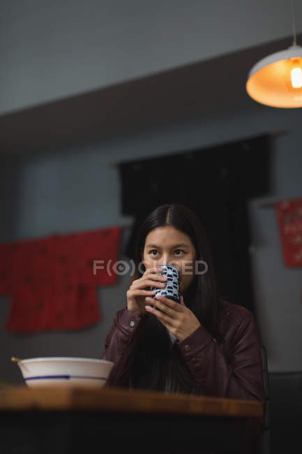 Mujer joven tomando té verde en el restaurante - foto de stock