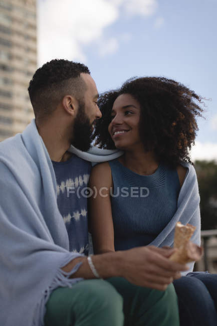 Smiling couple wrapped in shawl looking at each other — Stock Photo