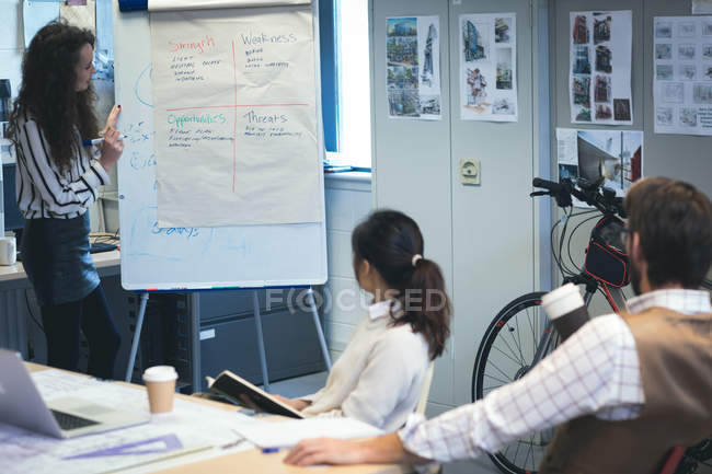 Executivo dando apresentação ao colega sobre flip chart no escritório — Fotografia de Stock