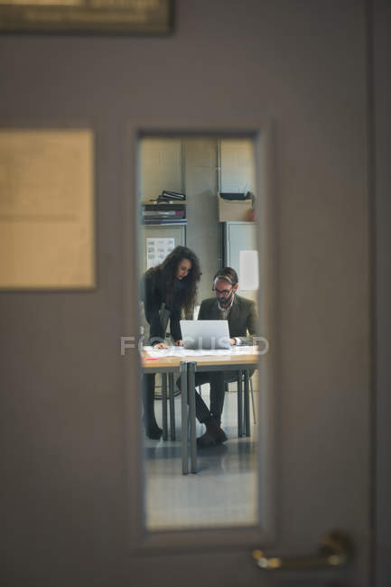 Руководители обсуждают за ноутбуком в современном офисе — стоковое фото