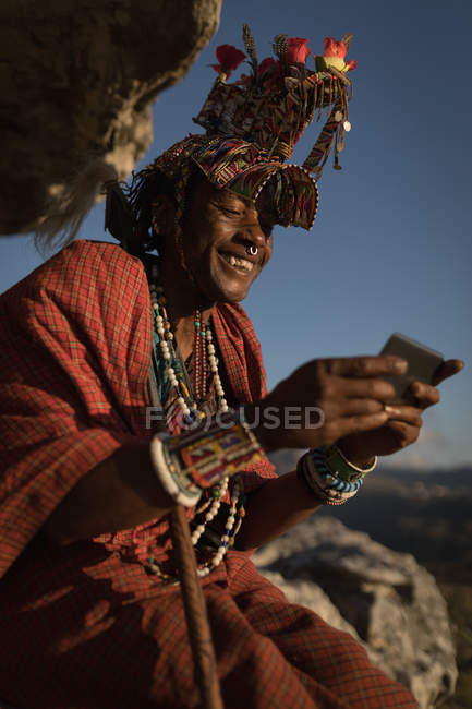 Massai-Mann in traditioneller Kleidung mit Handy auf dem Land — Stockfoto