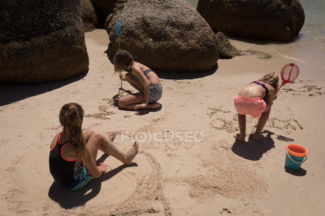 Брати і сестри, граючи в піску на пляжі на сонячний день — стокове фото