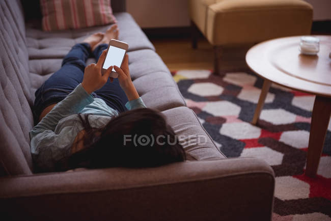 Mulher usando telefone celular na sala de estar em casa — Fotografia de Stock
