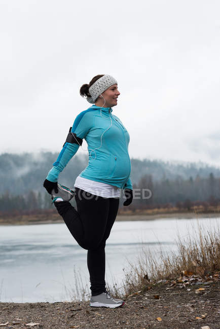 Pregnant woman performing stretching exercising in the park — Stock Photo