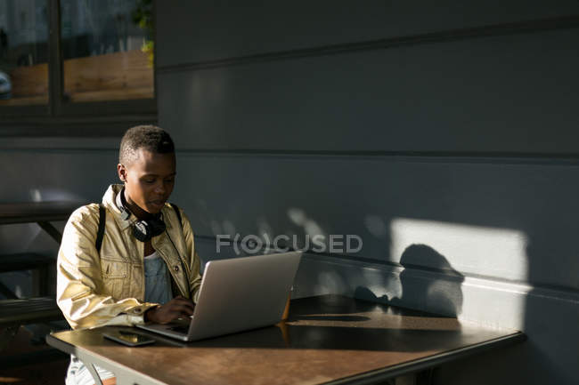 Mujer joven usando el ordenador portátil en la cafetería al aire libre - foto de stock
