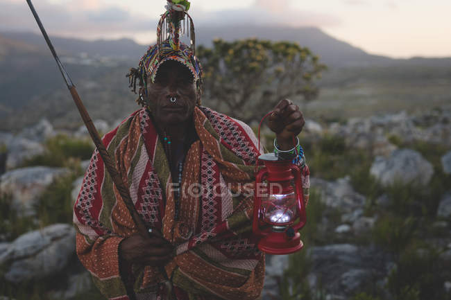 Retrato del hombre maasai sosteniendo linterna en el campo - foto de stock