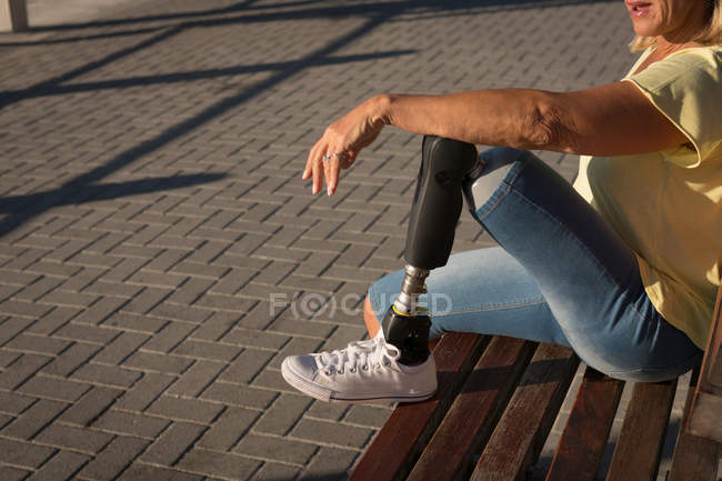 Disabled woman relaxing on bench in sunlight. — Stock Photo
