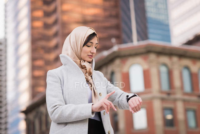 Femme en hijab en utilisant smartwatch en ville — Photo de stock