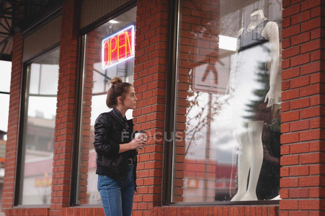 Schönes Mädchen sieht Kleid auf Schaufensterpuppe in der Anzeige — Stockfoto