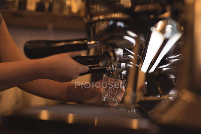 Barista preparando café en el mostrador en la cafetería - foto de stock