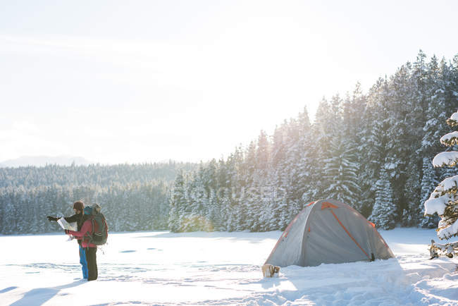 Пара туристів, які дивляться на карту в сніговий пейзаж взимку . — стокове фото