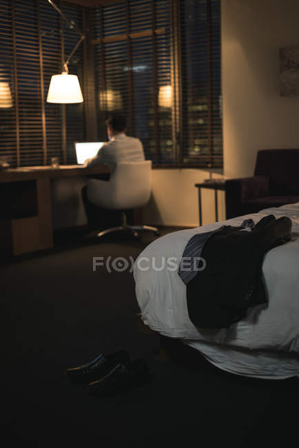 Businessman using laptop in bedroom at hotel — Stock Photo