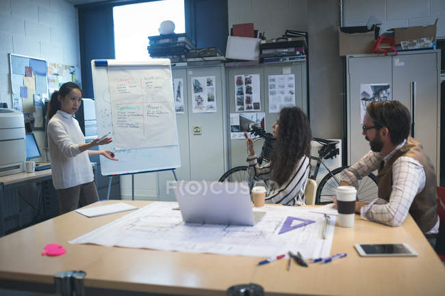 Executivo dando apresentação ao colega sobre flip chart no escritório — Fotografia de Stock