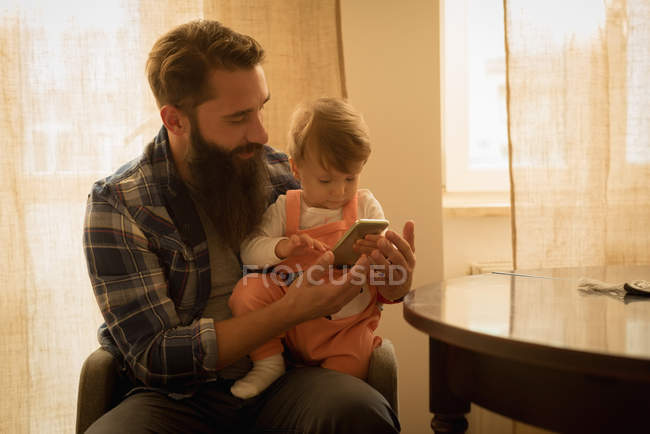 Father and son using mobile phone at home — Stock Photo