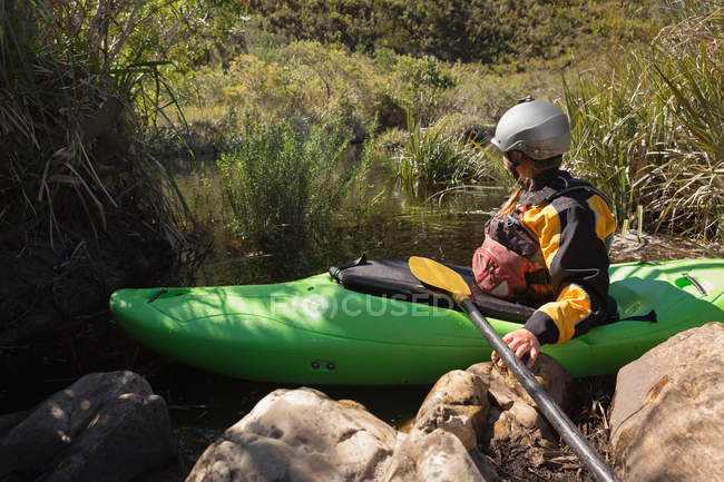 Frau bereitet sich bei Sonnenlicht auf Kajakfahren im Fluss vor. — Stockfoto