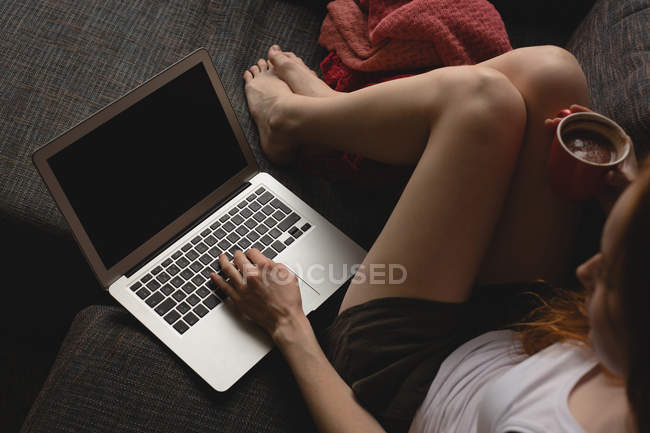 Woman using laptop while having coffee at home — Stock Photo