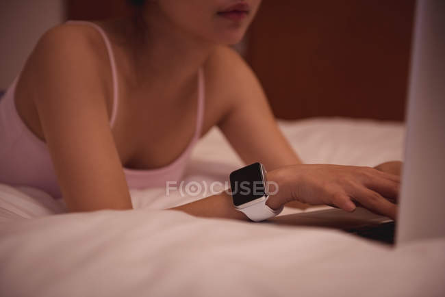 Woman using laptop in bedroom at home — Stock Photo