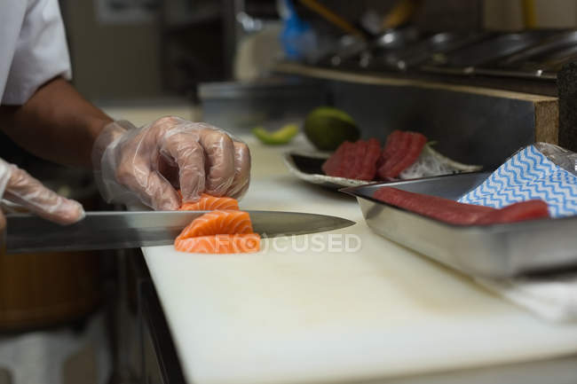 Средняя часть шеф-повара готовит суши на кухне в ресторане — стоковое фото
